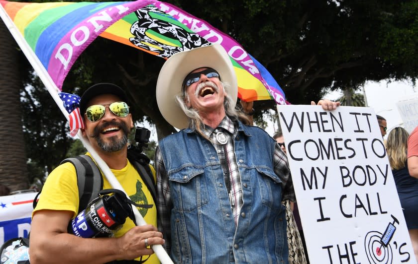 LOS ANGELES, CA. August 29, 2021: Two men share a laugh at a rally near the Santa Monica Pier for a "worldwide rally for freedom" Sunday. Hundreds of people attended the event at Tongva Park. (Wally Skalij/Los Angeles Times)