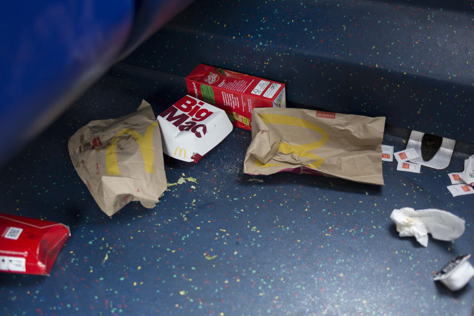 Dropped McDonalds packaging and food remains on the floor of a London bus.