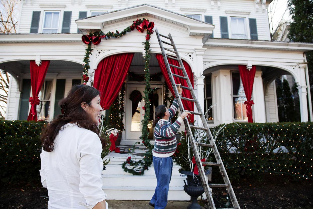 couple using ladder to put up christmas decorations