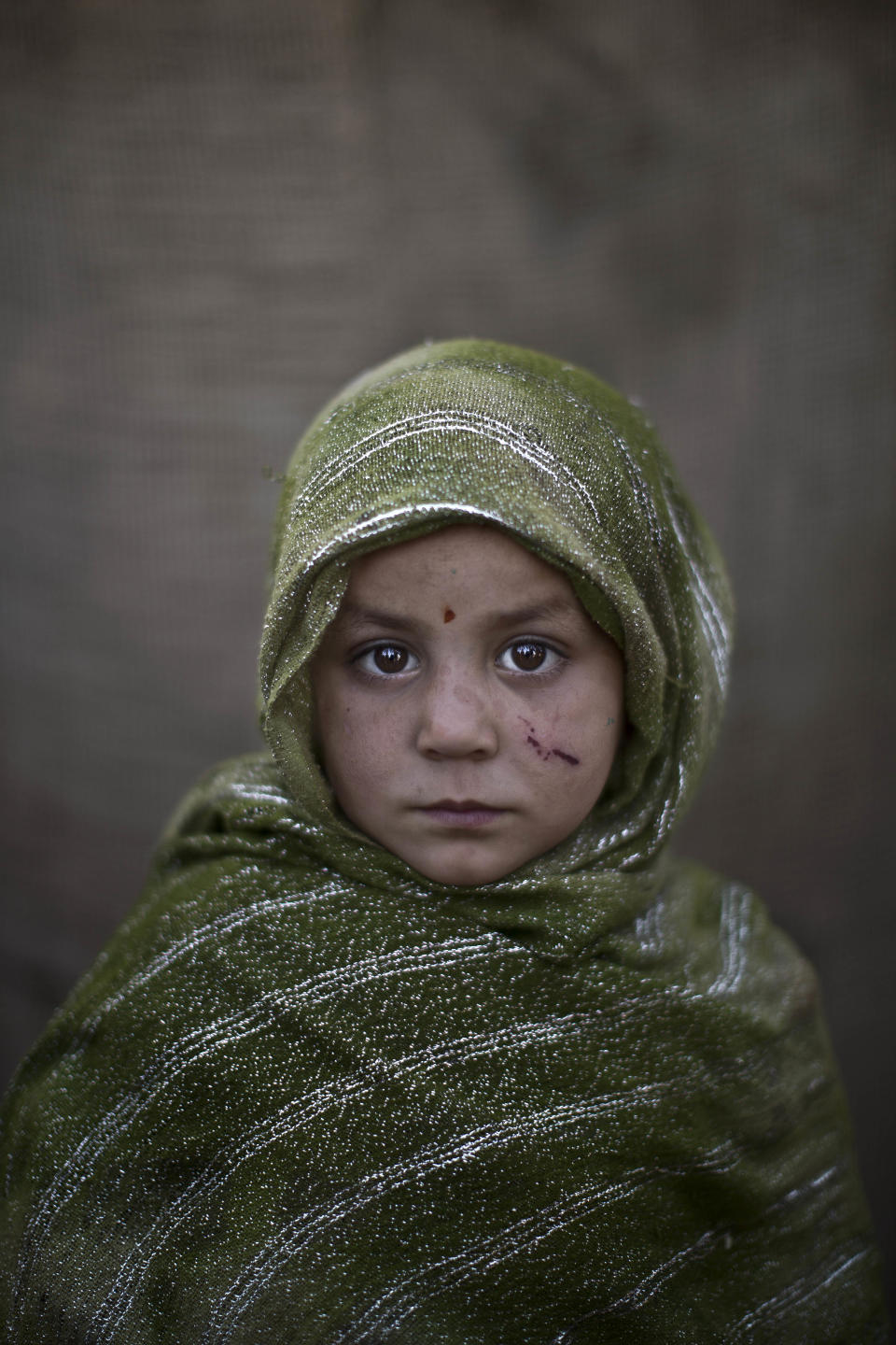 In this Monday, Jan. 27, 2014 photo, Afghan refugee girl, Madina Juma'a, 4, poses for a picture, while playing with other children in a slum on the outskirts of Islamabad, Pakistan. For more than three decades, Pakistan has been home to one of the world’s largest refugee communities: hundreds of thousands of Afghans who have fled the repeated wars and fighting their country has undergone. Since the 2002 U.S.-led invasion of Afghanistan, some 3.8 million Afghans have returned to their home country, according to the U.N.’s refugee agency. (AP Photo/Muhammed Muheisen)