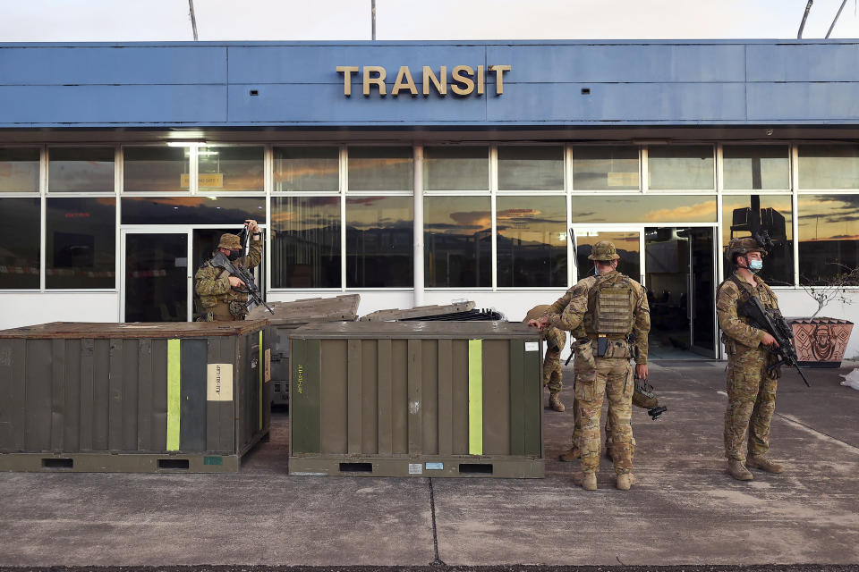 Australian soldiers stand outside the airport in Honiara, Solomon Islands, Saturday, Nov. 27, 2021. Violence receded in the capital of the Solomon Islands, but the government showed no signs of attempting to address the underlying grievances that sparked two days of riots, including concerns of the country's increasing links with China. (Gary Ramage via AP)