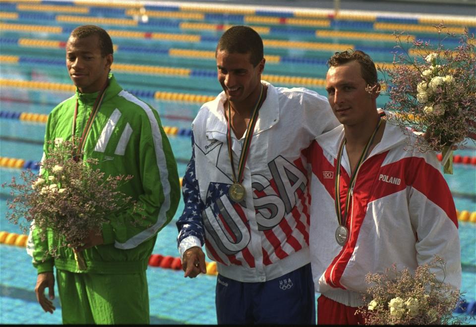 FILE - Pablo Morales, center, from the UnitesStates, displays the gold medal he won in the Olympic men's 100-meter butterfly in Barcelona, July 27, 1992. Morales is flanked by runners-up Rafal Szukala, right, from Poland, who took the silver medal, and Anthony Nesty, left, from Suriname, who won the bronze. In a sport still struggling to diversify, Nesty is a significant presence on the pool deck at the U.S. national championships. (AP Photo/Russell Mcphedran, File)