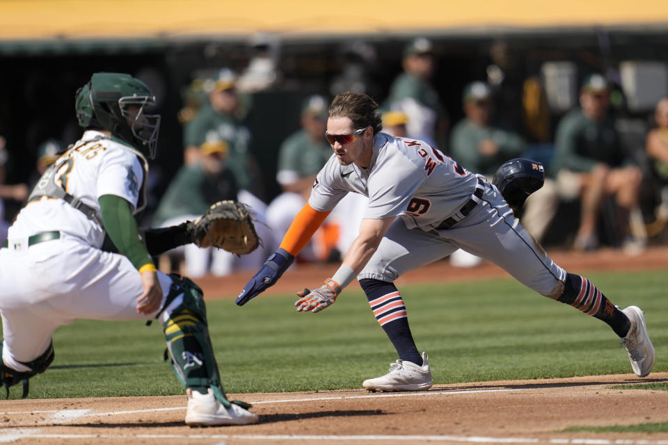 Detroit Tigers' Zach McKinstry, right, slides home to score against Oakland Athletics catcher Shea Langeliers during the third inning of a baseball game in Oakland, Calif., Saturday, Sept. 23, 2023. (AP Photo/Jeff Chiu)