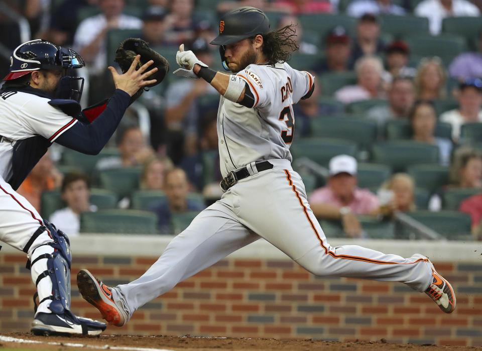 San Francisco Giants shortstop Brandon Crawford races the throw home to Atlanta Braves catcher Travis d' Arnaud during the fourth inning of a baseball game on Tuesday, June 21, 2022, in Atlanta. Crawford was called out on the play but after a review was ruled safe to take a 6-5 lead. (Curtis Compton Atlanta Journal-Constitution via AP)