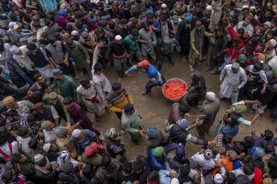 Volunteers carry a tub of sweetened rice before distributing among devotees outside the forest shrine of Sufi saint Mian Nizamuddin Kiyanwi in Baba Nagri, northeast of Srinagar, Indian controlled Kashmir, Saturday, June 8, 2024. (AP Photo/Dar Yasin)