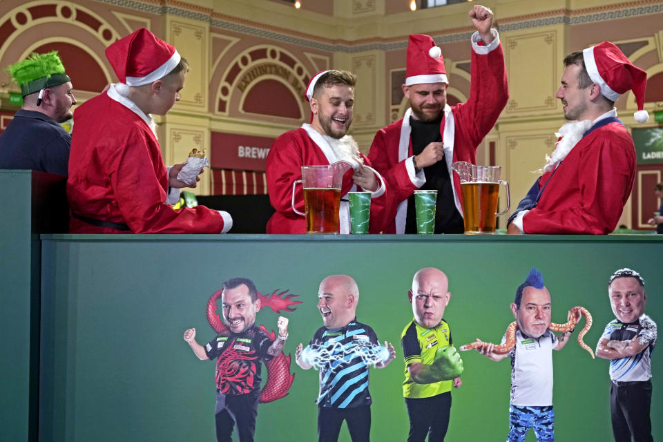 Darts fans dressed as Father Christmas enjoy a drink outside the main hall on day eight of the World Darts Championship, at Alexandra Palace in London, Friday, Dec. 22, 2023. (AP Photo/Kin Cheung)