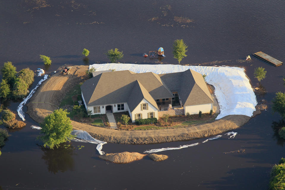 VICKSBURG, MS - MAY 18: A levee protects a home surrounded by floodwater from the Yazoo River May 18, 2011 near Vicksburg, Mississippi. The flooded Mississippi River is forcing the Yazoo River to top its banks where the two meet near Vicksburg causing towns and farms upstream on the Yazoo to flood. The Mississippi River at Vicksburg is expected to crest May 19. Heavy rains have left the ground saturated, rivers swollen, and have caused widespread flooding along the Mississippi River from Illinois to Louisiana. (Photo by Scott Olson/Getty Images)