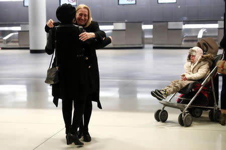 Alma Kashkooli, (12), from Iran who has a severe medical condition, sits in a stroller as her mother Farimeh Kashkooli (front L) embraces a children's aid who escorted Alma to the U.S. from Istanbul Turkey upon their arrival at New York's John F. Kennedy International Airport in New York, February 6, 2017. REUTERS/Mike Segar