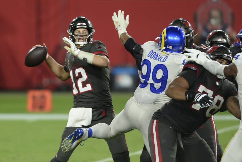 Tampa Bay Buccaneers quarterback Tom Brady (12) passes around Los Angeles Rams defensive end Aaron Donald (99) during the first half of an NFL football game Monday, Nov. 23, 2020, in Tampa, Fla. (AP Photo/Jason Behnken)