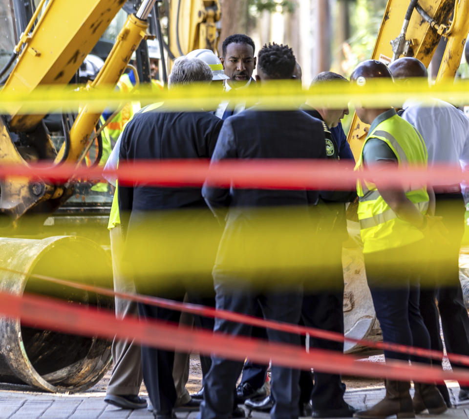 Atlanta Mayor Andre Dickens listens as crews continue to work on a broken main on West Peachtree Street in Midtown, with nearby residents warned of impacts to their water service as the crisis reached its fourth day Monday, June 3, 2024. Water had been gushing out of the broken main until Monday morning, when workers were seen pumping out water. (John Spink/Atlanta Journal-Constitution via AP)