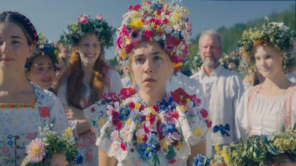 Five girls wearing floral crowns are looking at something