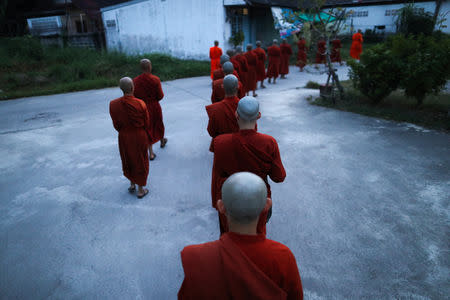 Novice monks walk in line to receive food offerings from people at the Songdhammakalyani monastery, Nakhon Pathom province, Thailand, December 7, 2018. REUTERS/Athit Perawongmetha