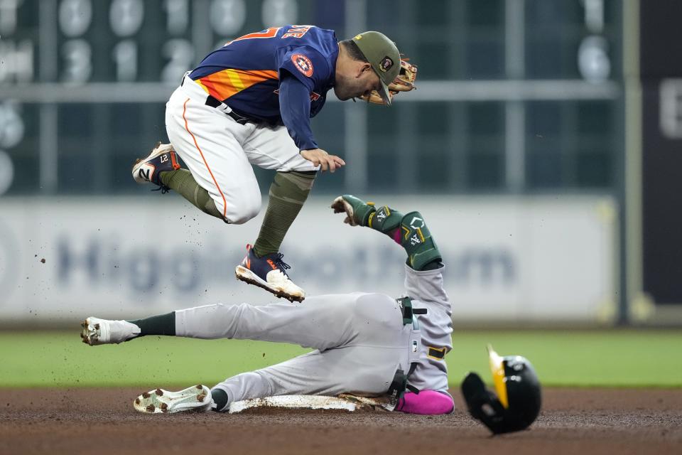 Oakland Athletics' Esteury Ruiz, right, slides safely into second base after hitting a double as Houston Astros second baseman Jose Altuve leaps over him during the sixth inning of a baseball game Sunday, May 21, 2023, in Houston. (AP Photo/David J. Phillip)