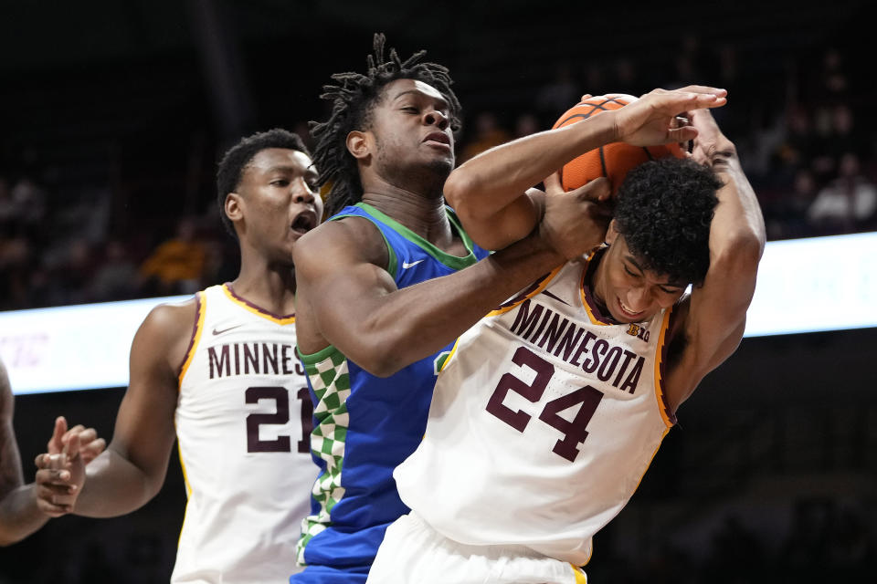 Florida Gulf Coast forward Keeshawn Kellman, center, and Minnesota guard Cam Christie (24) battle for possession during the second half of an NCAA college basketball game Saturday, Dec. 9, 2023, in Minneapolis. (AP Photo/Abbie Parr)