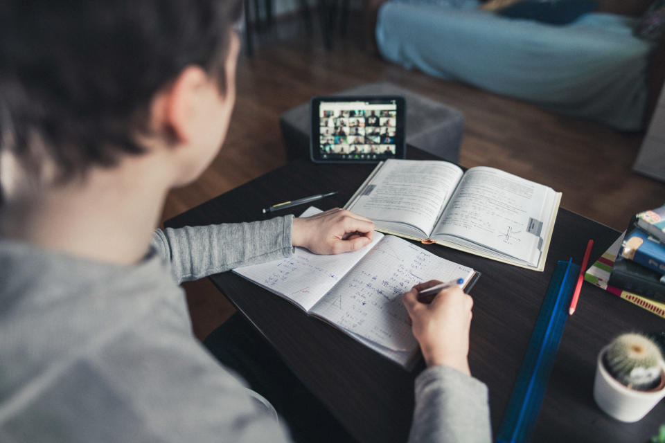 A student doing virtual learning with their tablet and books out