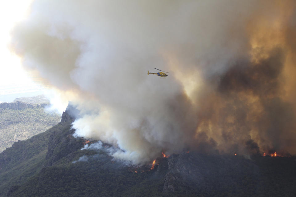 In this Thursday, Jan. 16, 2014 photo released by Victoria Country Fire Authority, a water bomber works over a large fire burning throughout Victoria's Grampians region. Fire authorities in Victoria said there are 68 fires burning at present with stronger winds expected Friday afternoon, urging residents in these affected regions to evacuate. (AP Photo/Country Fire Authority)