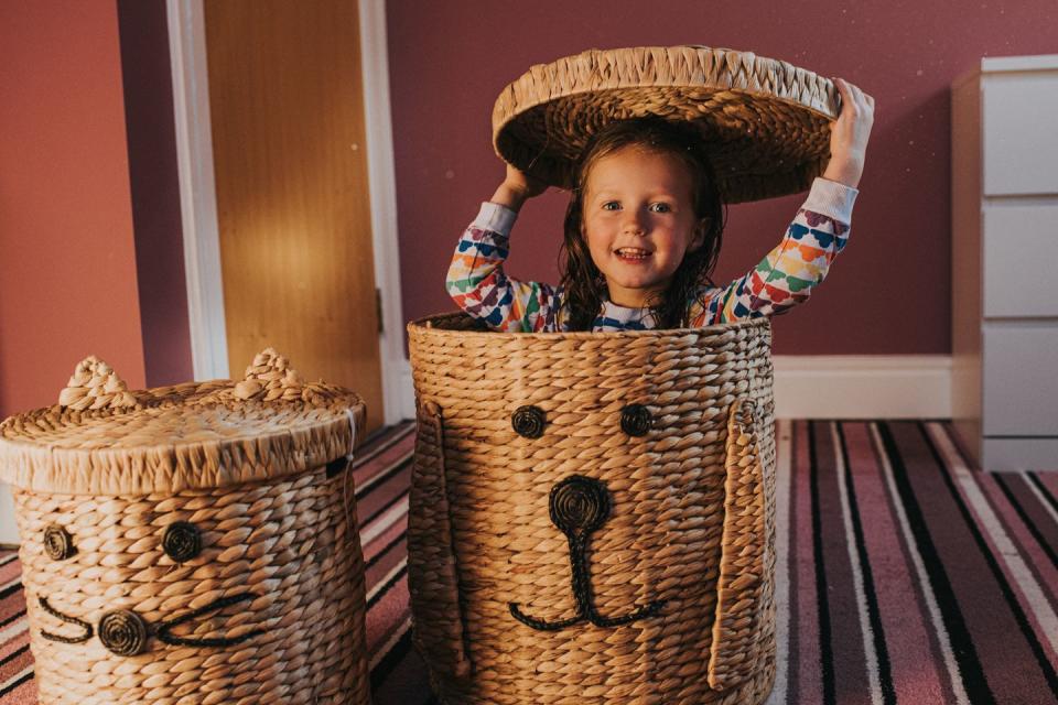 playful child hiding in a rattan laundry basket in bedroom fun activities for kids