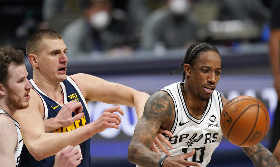 San Antonio Spurs forward DeMar DeRozan, right, fights for control of the ball with Spurs center Jakob Poeltl, left, and Denver Nuggets center Nikola Jokic, center, in the second half of an NBA basketball game Friday, April 9, 2021, in Denver. (AP Photo/David Zalubowski)