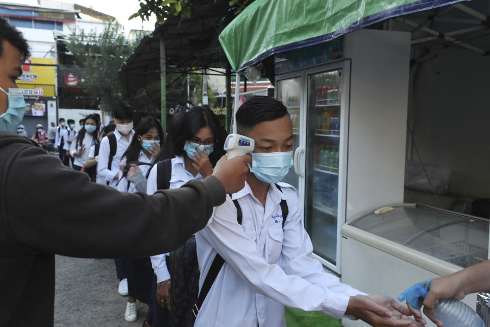 Students have their temperature checked and disinfect their hands to avoid the contact of coronavirus before their morning classes at Preah Sisowath high school, in Phnom Penh, Cambodia, Monday, Nov. 23, 2020. Cambodia on Monday reopened schools after the country banned all state-organized events in the capital and a neighboring province for two weeks to prevent the spread of the coronavirus after a number of people connected to a Hungarian official's visit tested positive in early the month of November. (AP Photo/Heng Sinith)