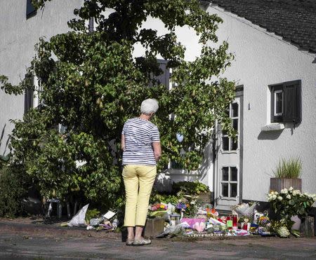 A woman looks at flowers placed in front of the house of a family who were all killed in Thursday's Malaysia Airlines Boeing 777 plane crash, in Neerkant, near Eindhoven July 19, 2014. REUTERS/Mischa Rapmund