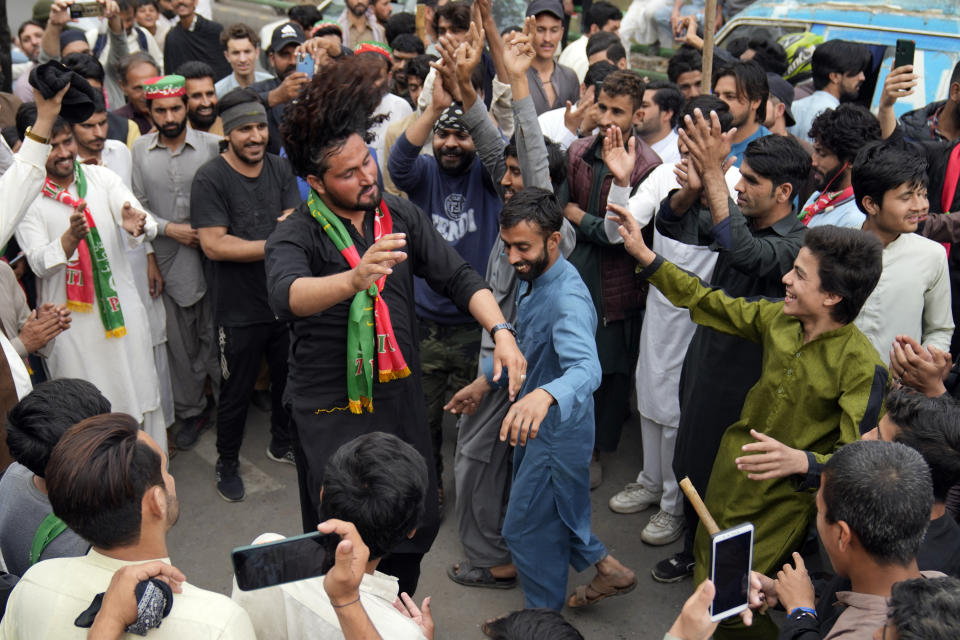 Supporters of former Prime Minister Imran Khan dance outside of the Khan house in Lahore, Pakistan, Sunday, March 19, 2023. Police in the Pakistani capital filed charges Sunday against former Prime Minister Imran Khan and 17 of his aides and scores of supporters, accusing them of terrorism and several other offenses after the ousted premier's followers clashed with security forces in Islamabad the previous day. (AP Photo/K.M. Chaudary)