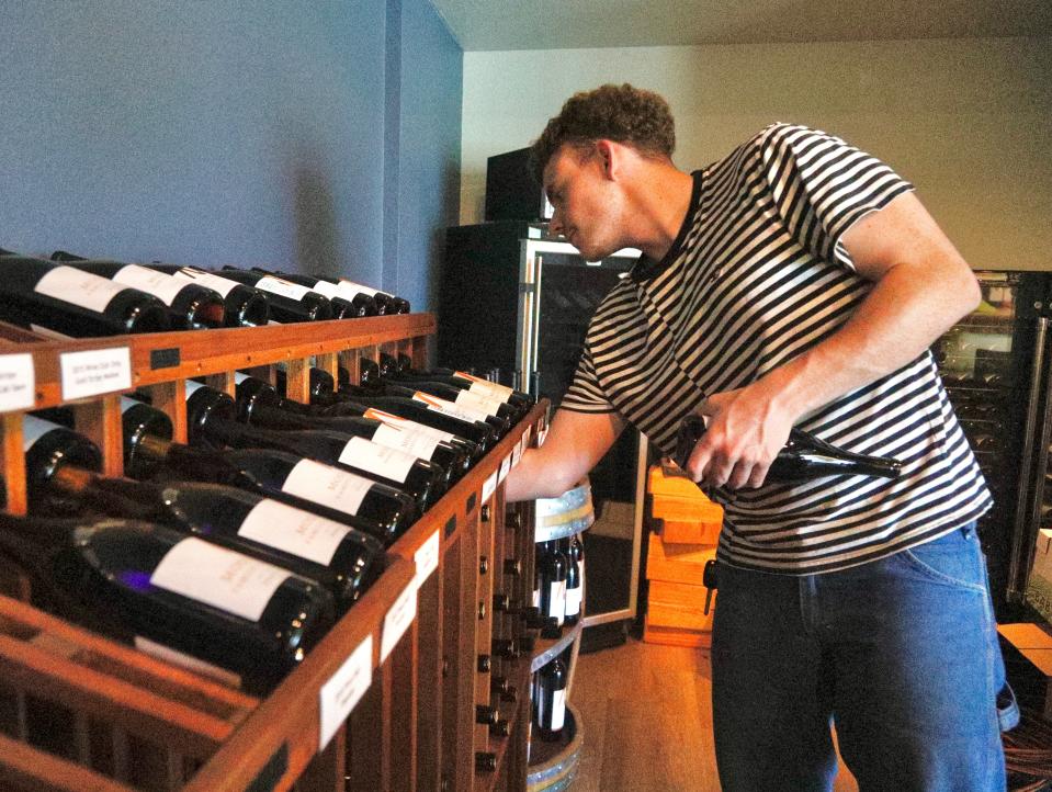 File photo - Jake Fitzgerald of Moseley Family Cellars restocks a rack in the tasting room at the winery in July 2022.