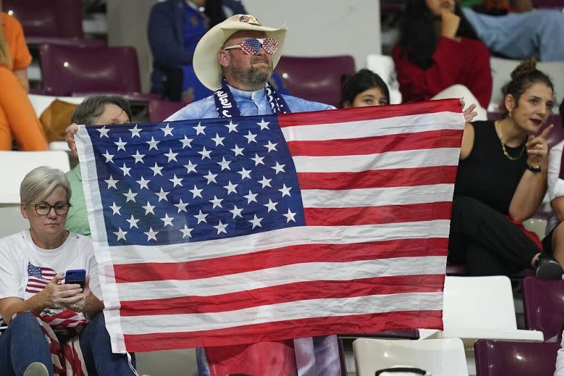 A US fan holds a flag of his country ahead of the start of the World Cup match between the Netherlands and the US, in Doha, December 2022