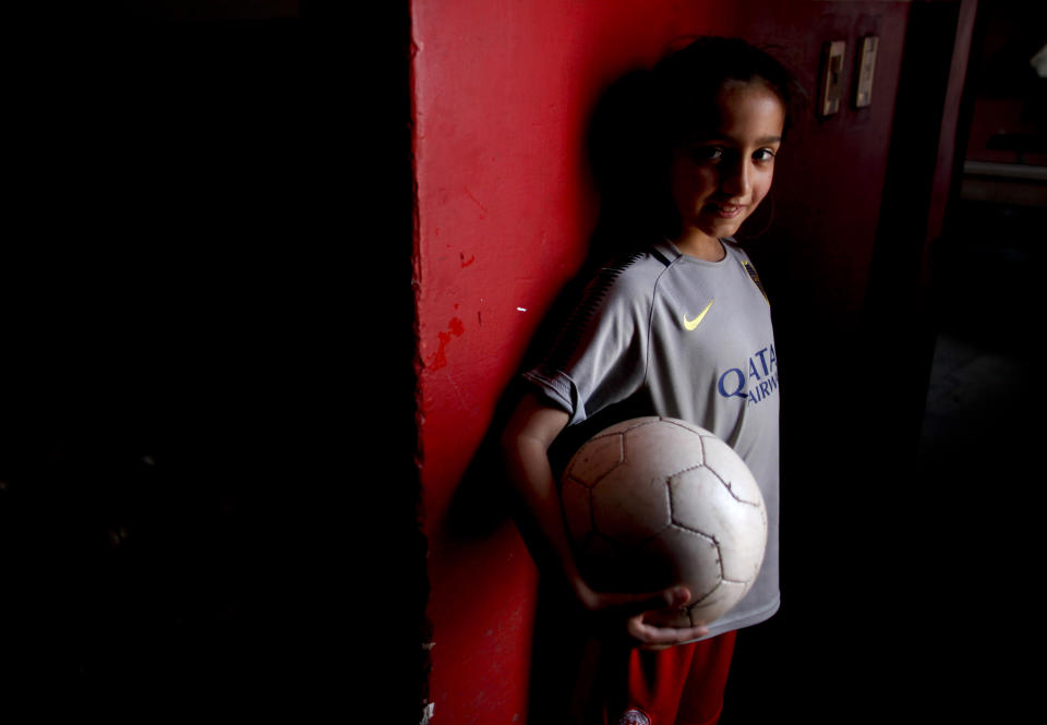 In this Sept. 8, 2018 photo, 7-year-old Candelaria Cabrera poses for a portrait holding a soccer ball in Chabas, Argentina. She was 3 years old when her parents gave her her first ball. Her desire to play soccer has called attention to the obstacles women face in the sport in Argentina. (AP Photo/Natacha Pisarenko)