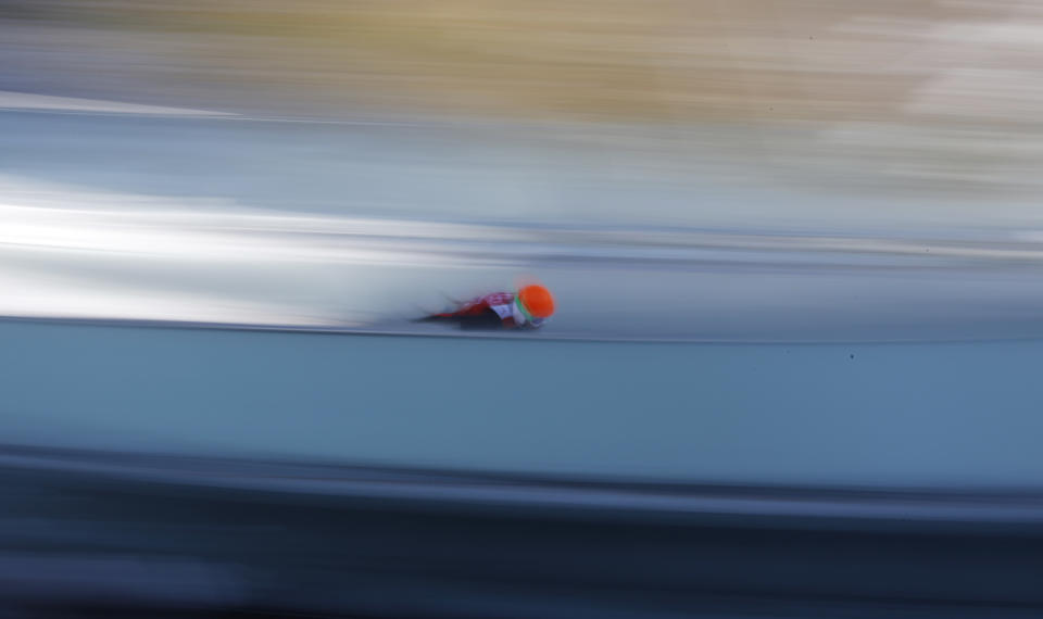 In this slow shutter speed photo an unidentified athlete starts an attempt during the men's normal hill ski jumping training at the 2014 Winter Olympics, Friday, Feb. 7, 2014, in Krasnaya Polyana, Russia. (AP Photo/Matthias Schrader)