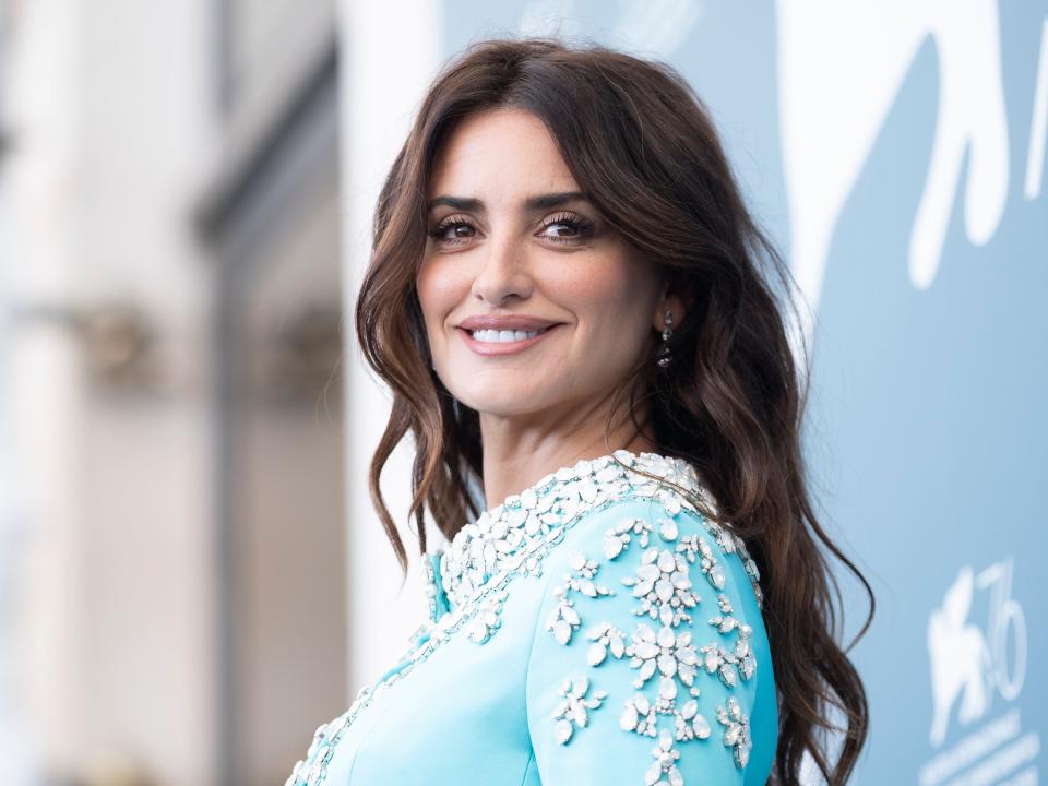 Penelope smiling in a teal top in front of a backdrop.