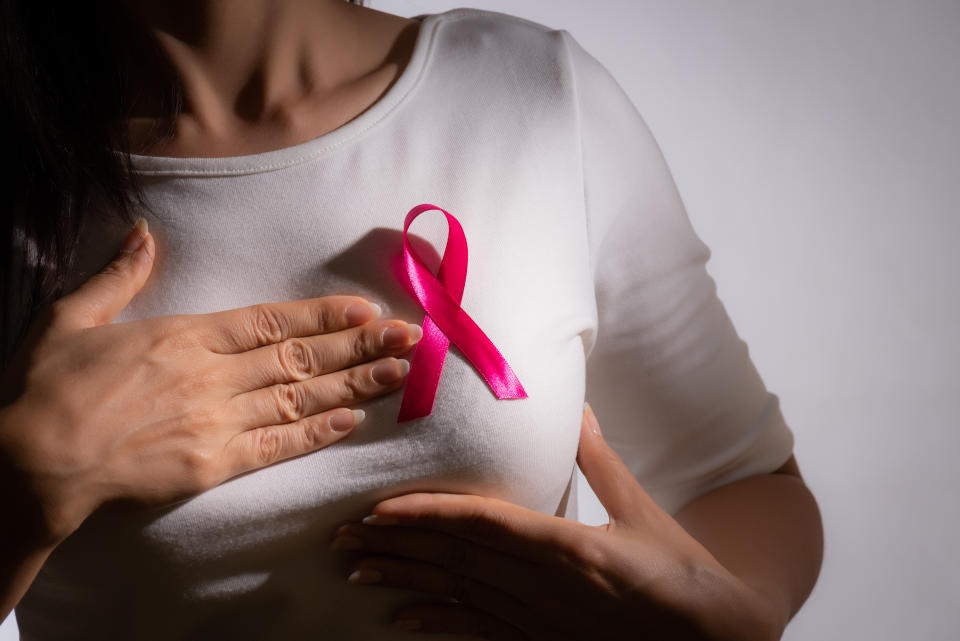 Midsection Of Woman Touching Breast While Standing Against Gray Background