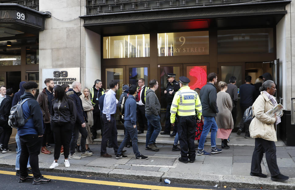 Police officers and security watch as people re-enter a building after a stabbing incident in central London, Friday, Nov. 2, 2018. British police say two people have been stabbed and a man has been arrested at an address in central London that is home to the offices of Sony Music. (AP Photo/Alastair Grant)