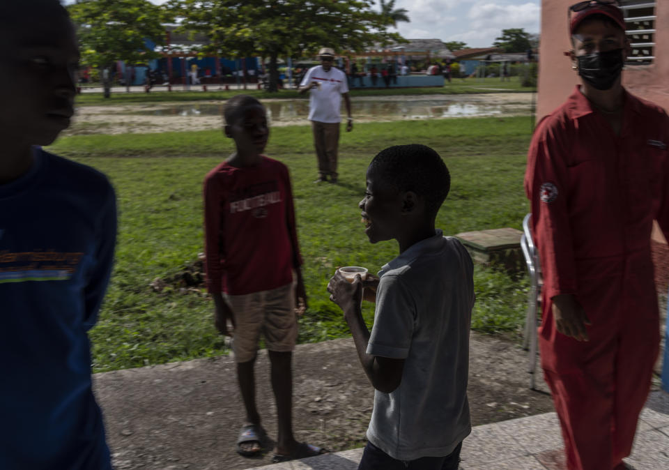 A young Haitian migrant boy smiles after getting his breakfast at a campground being used to house a large group of Haitian migrants in Sierra Morena in Cuba's Villa Clara province, Thursday, May 26, 2022. A vessel carrying more than 800 Haitians trying to reach the United States wound up instead on the coast of central Cuba, in what appeared to be the largest group seen yet in a swelling exodus from crisis-stricken Haiti. (AP Photo Ramon Espinosa)