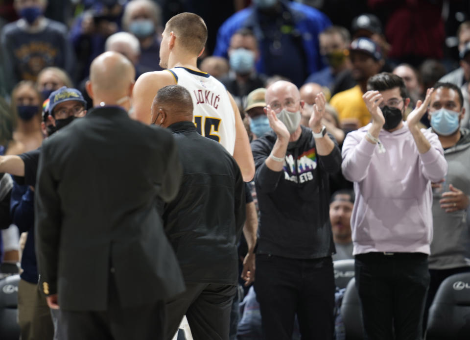 Fans applaud as Denver Nuggets center Nikola Jokic, top center left, is escorted from the court following his ejection for being involved in a scrum with Miami Heat forward Markieff Morris in the second half of an NBA basketball game Monday, Nov. 8, 2021, in Denver. (AP Photo/David Zalubowski)