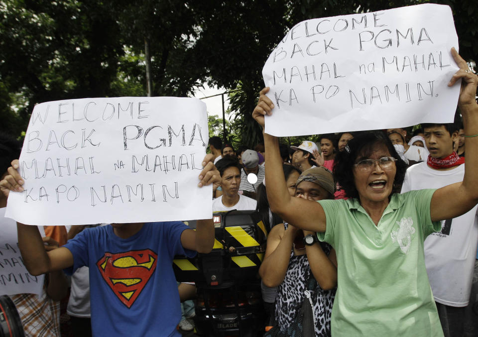 Supporters of former Philippine President Gloria Macapagal Arroyo hold up slogans that read: "Welcome back President Gloria Macapagal Arroyo, PGMA, we love you very much." as they await her release outside a government hospital in suburban Quezon City, north of Manila, Philippines, Wednesday July 25, 2012. Arroyo on Wednesday released on bail after a judge found weak evidence linking her to an election sabotage case. (AP Photo/Aaron Favila)