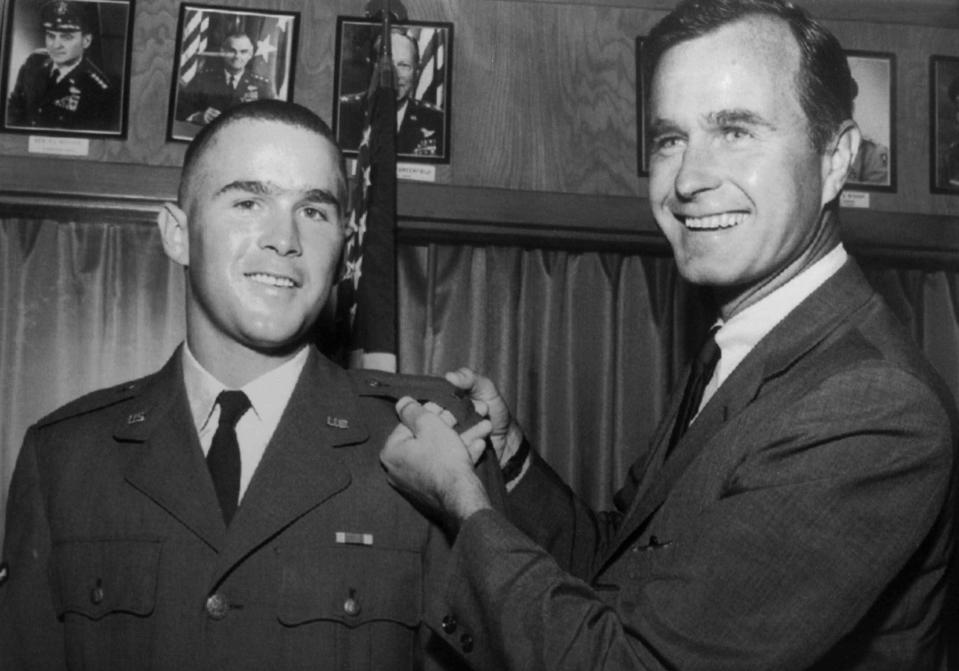 FILE - In this 1968 file photo provided by the Texas National Guard, George H.W. Bush, right, is about to pin a lieutenant bar on his son, George W. Bush, after the younger Bush was made an officer in the Texas Air National Guard in Ellington Field, Texas. Bush died at the age of 94 on Friday, Nov. 30, 2018, about eight months after the death of his wife, Barbara Bush. (AP Photo, File)