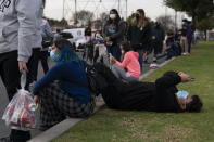 FILE — Robert Rodriguez, 14, looks at his phone while waiting in line for a test at a mobile COVID-19 testing site in Paramount, Calif., Wednesday, Jan. 12, 2022. California is showing signs that it may have turned the corner on the latest omicron wave of the corona virus pandemic with cases falling and hospitalizations short of the overwhelming deluge that officials had predicted earlier. (AP Photo/Jae C. Hong, File)