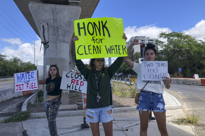 Protestors upset with the U.S. Department of Defense's response to the leak of jet fuel into the water supply hold signs outside the gate at Joint Base Pearl Harbor-Hickam, Hawaii, Friday, Sept. 30, 2022. (AP Photo/Audrey McAvoy)