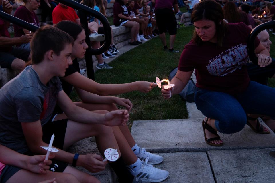 West Elementary School social studies teacher Amber Cox lights a candle for Lindsey Lilleston, 14, during a vigil for 11-year-old Camrynn McMichael at the Mount Vernon Riverfront Thursday evening, July 7, 2022. The youngster died July 3rd due to a fireworks accident. Cox was one of McMichael's teachers at the school.