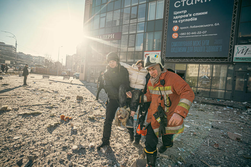 A rescuer and policeman carry an injured woman from a multi-story residential building in Kyiv, after a Russian rocket hit on Feb. 26, 2022.<span class="copyright">Pavlo Petrov</span>