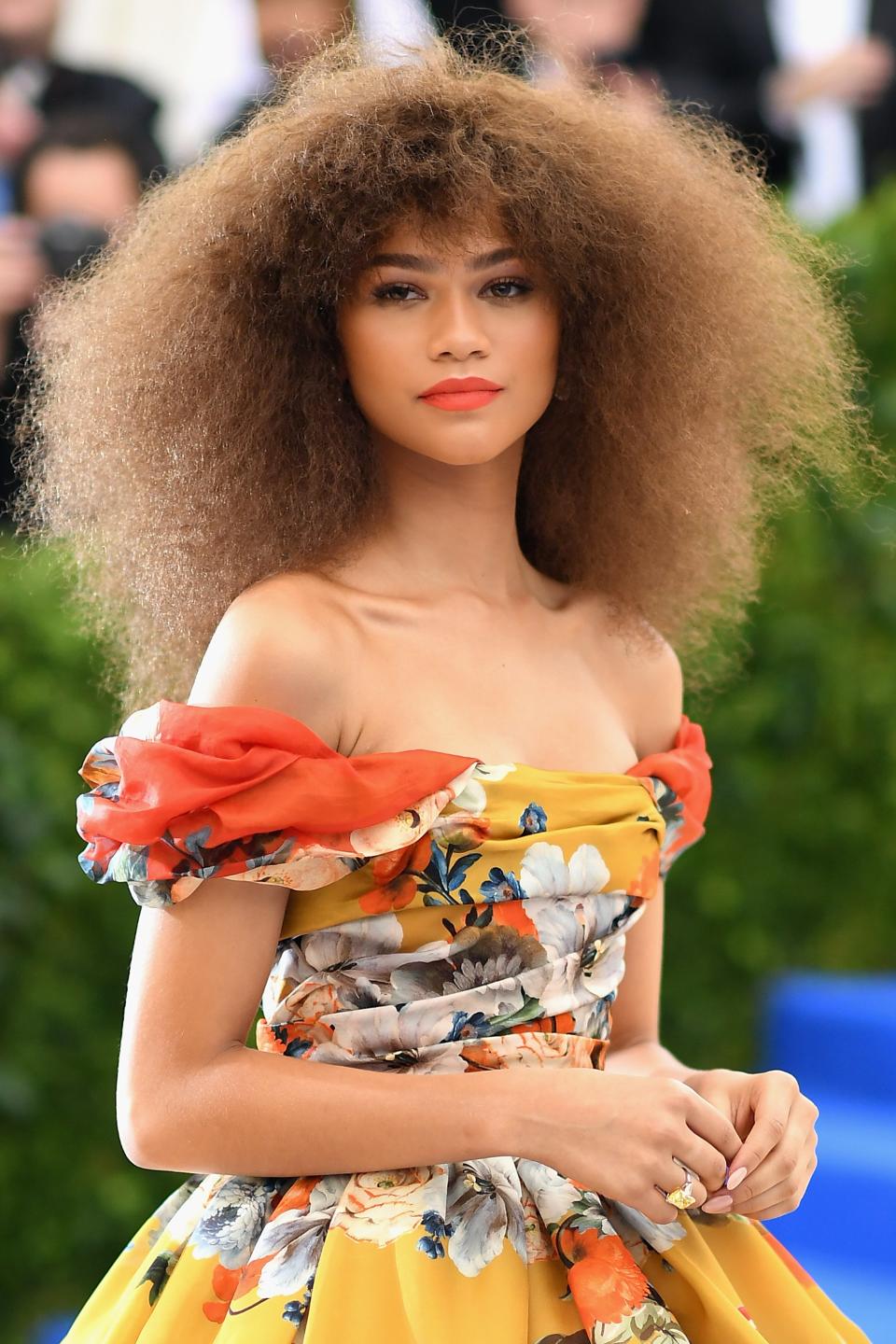 Zendaya in a floral off-the-shoulder gown posing at an event
