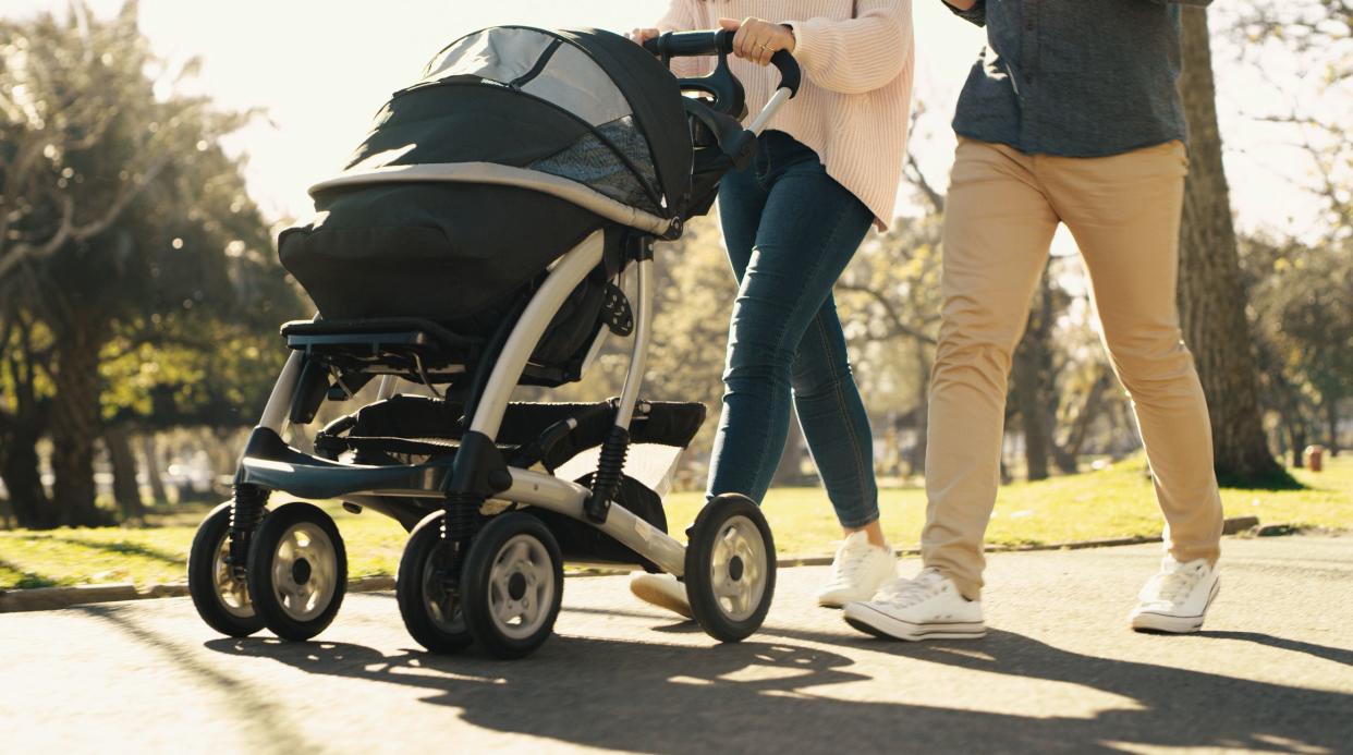 Parents, baby stroller and exercise with a young man and woman pushing a pram while walking through a park on a sunny day. Closeup feet of a young family out for an active leisure stroll in summer