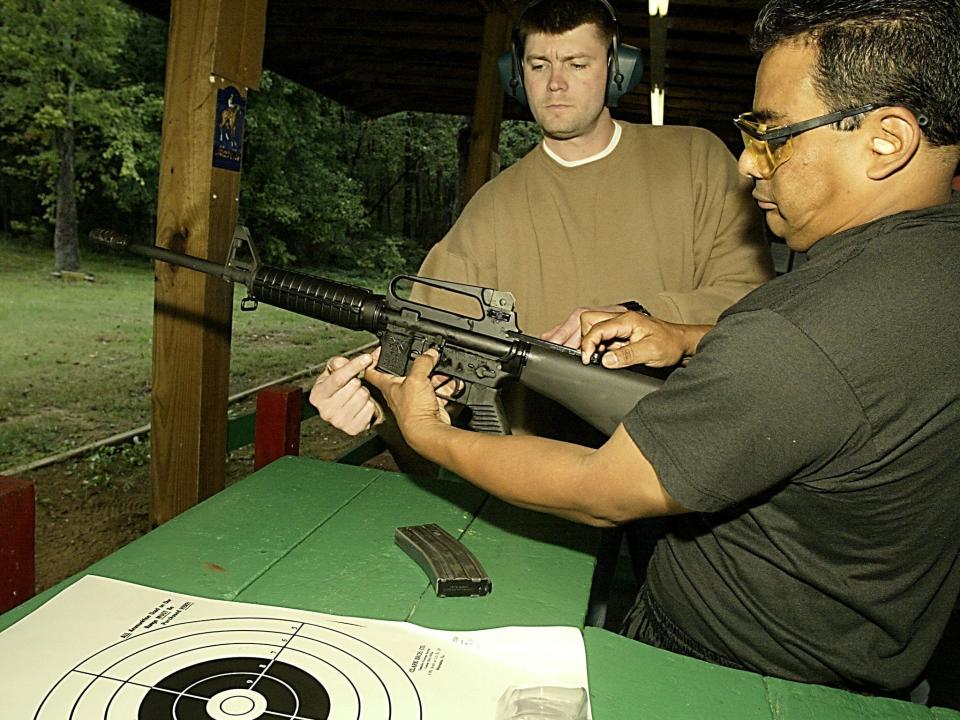 A weapons expert shows an officer how to use an AR-15 at a firing range in 2002.