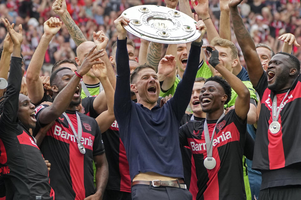 FILE - Leverkusen's head coach Xabi Alonso celebrates with the trophy as his team won the German Bundesliga, after the German Bundesliga soccer match between Bayer Leverkusen and FC Augsburg at the BayArena in Leverkusen, Germany, Saturday, May 18, 2024. A low-rise city of 167,000 that grew up around the factories of the pharmaceuticals giant Bayer, Leverkusen has little to draw tourists besides its internationally famed soccer club. The team finished an entire German Bundesliga season unbeaten Saturday and is now targeting trophies in the Europa League and German Cup. (AP Photo/Martin Meissner, File)