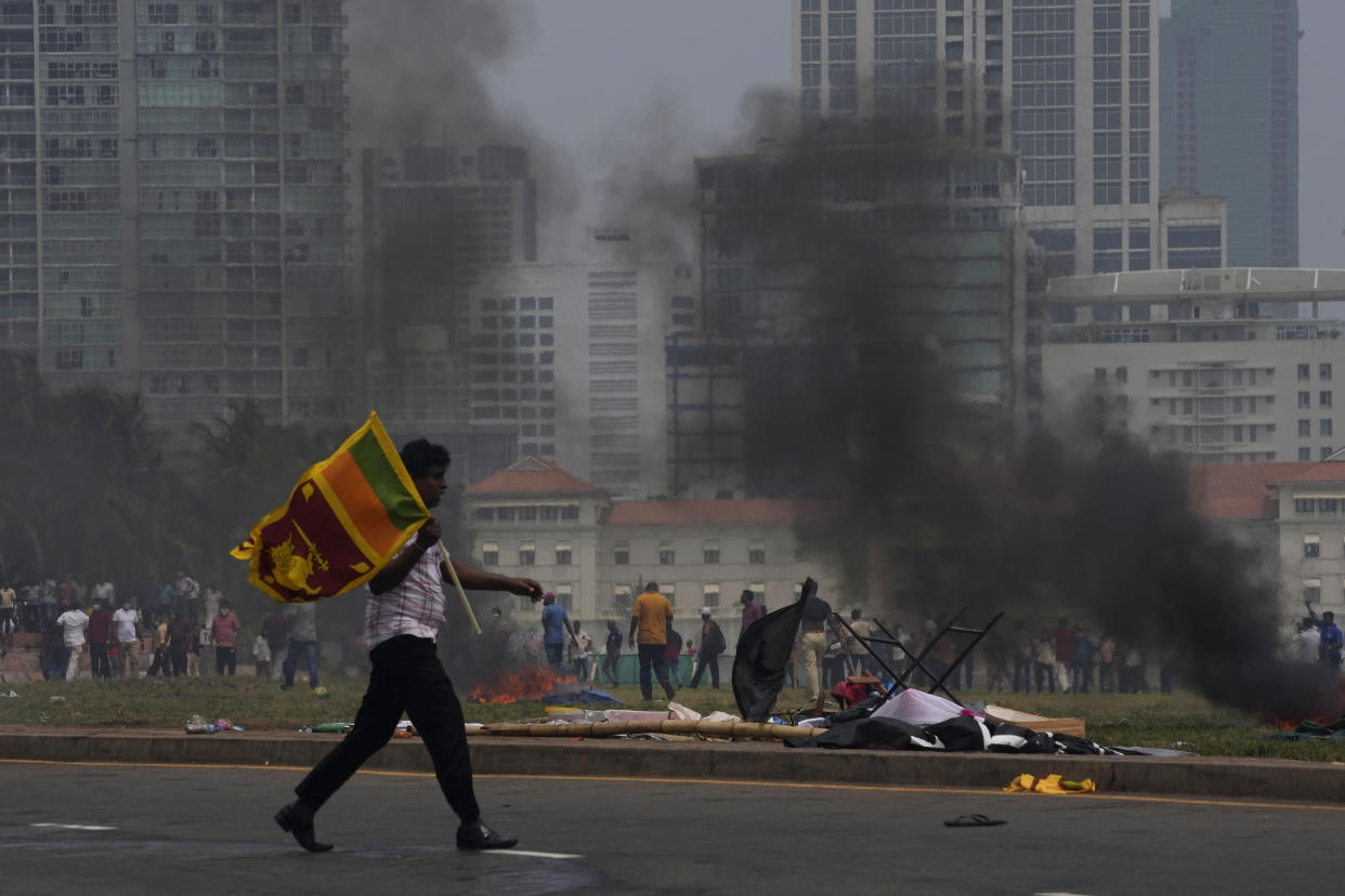 A Sri Lankan government supporter carries a national flag after attacking the anti-government protesters outside president's office in Colombo, Sri Lanka, Monday, May 9, 2022. Government supporters on Monday attacked protesters who have been camped outside the offices of Sri Lanka's president and prime minster, as trade unions began a “Week of Protests” demanding the government change and its president to step down over the country’s worst economic crisis in memory. (AP Photo/Eranga Jayawardena)