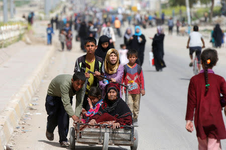 Displaced Iraqis push a wheelbarrow carrying a woman as they flee after a battle between the Iraqi Counter Terrorism Service and Islamic State militants in western Mosul, Iraq, April 22, 2017. REUTERS/Muhammad Hamed