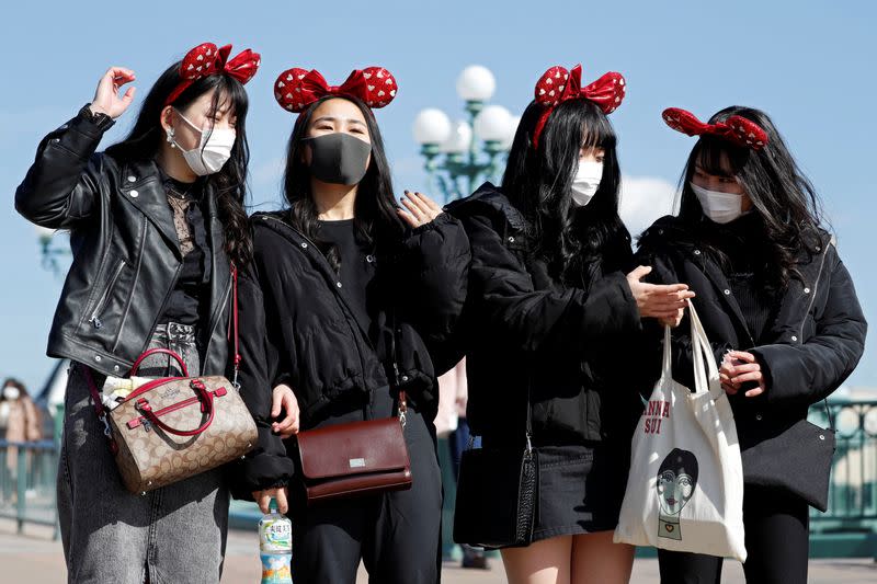 Visitors wearing protective face masks and Minnie Mouse costumes, following an outbreak of the coronavirus, are seen outside Tokyo Disneyland in Urayasu