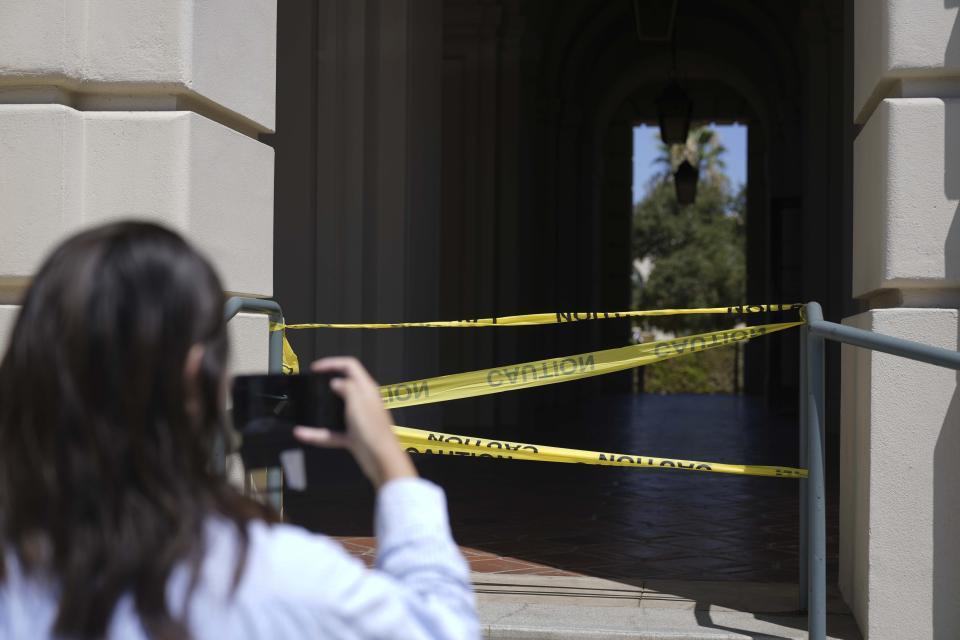 A passerby takes a photo of police caution tape closing off a part of Pasadena City Hall on Monday, Aug. 12, 2024, in Pasadena, Calif. (AP Photo/Ryan Sun)