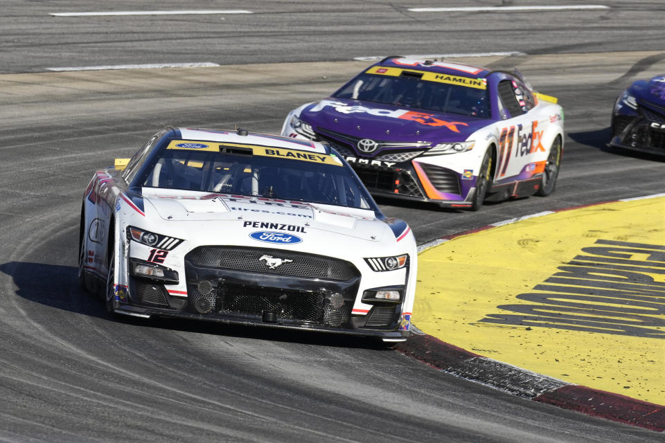 Ryan Blaney (12) leads Denny Hamlin (11) out of Turn 2 during a NASCAR Cup Series auto race at Martinsville Speedway in Martinsville, Va., Sunday, Oct. 29, 2023. (AP Photo/Chuck Burton)