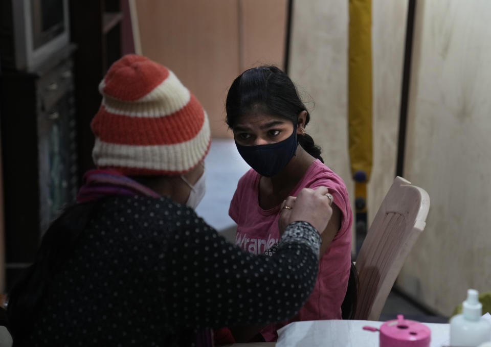 A health worker administers Covid-19 vaccination to a girl, in New Delhi, India, Friday, Jan. 28, 2022. Indian health officials said that the first signs of COVID-19 infections plateauing in some parts of the vast country were being seen, but cautioned that cases were still surging in some states. (AP Photo/Manish Swarup)